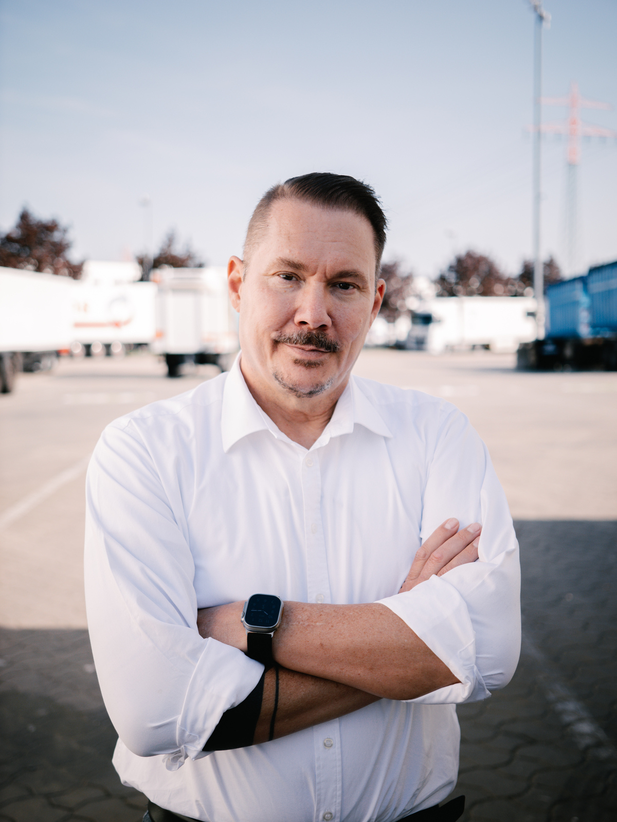 Alternatives Gründerporträt von Tobias Stancke vor Lkw auf einem Speditionshof